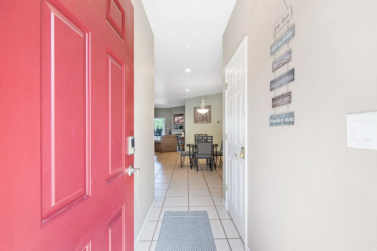 This image captures the entryway with a distinctive red front door leading into a welcoming dining area, adorned with decorative wall hangings. The scene hints at the property’s first impression and the thoughtful decor that greets guests upon arrival.