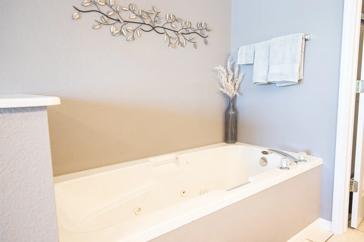 A well-appointed bathroom featuring a bathtub ideal for relaxing soaks, decorative wall art, plush towels, and thoughtfully placed dried flowers, all contributing to a spa-like atmosphere.