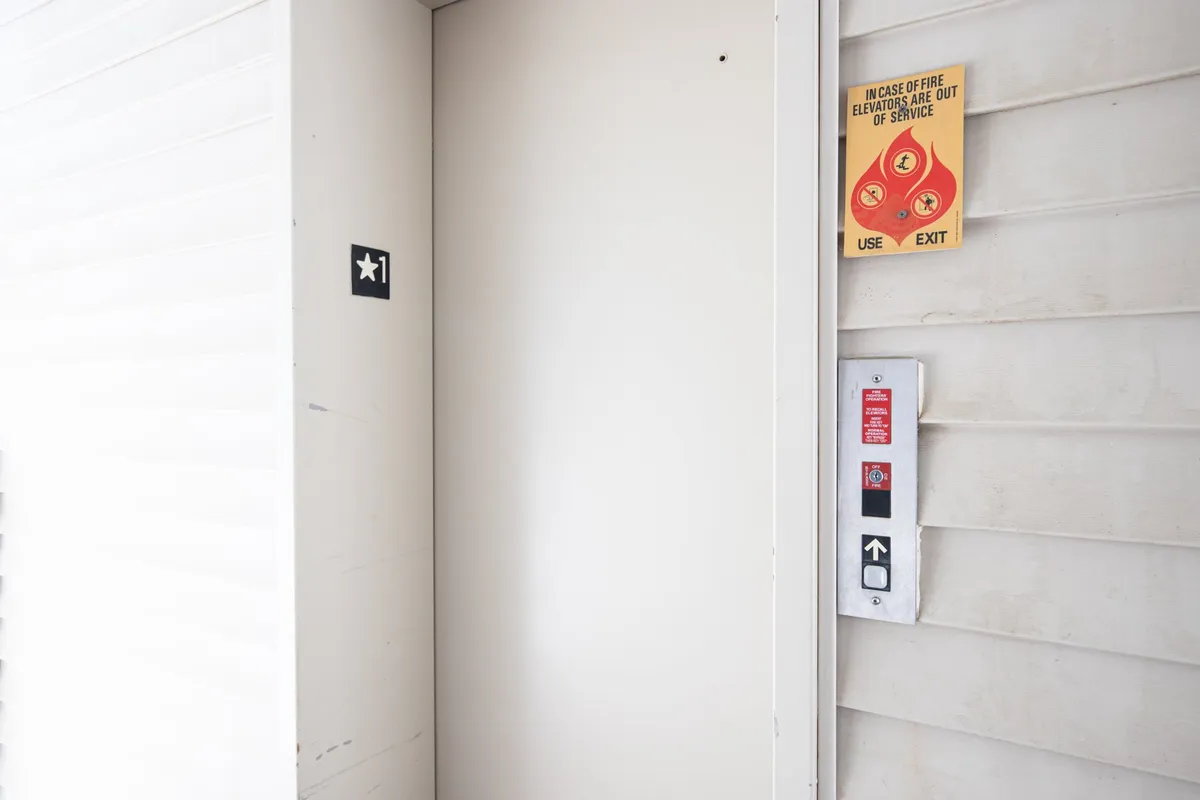 A close-up interior image of the elevator door and button panel, featuring clear signage and a neutral, clean atmosphere. The shot conveys accessibility and convenience for guests moving throughout the property.