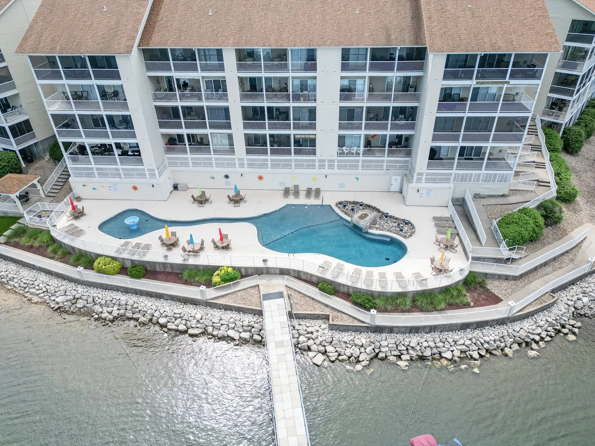 The exterior image features a swimming pool with lounge chairs, a clear view of the waterfront, and a pathway leading to the shore. The scene is lively yet relaxed, illustrating options for both water-based recreation and relaxation after a day on the lake.