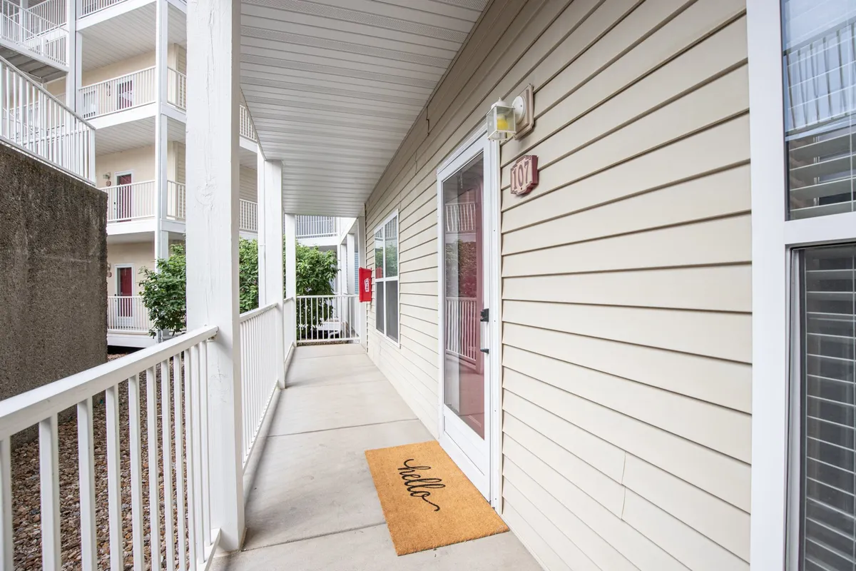 A welcoming front entrance featuring a 'hello' doormat, a prominent front door, and the visible house number. The scene exudes warmth and the anticipation of arrival at a cozy retreat.