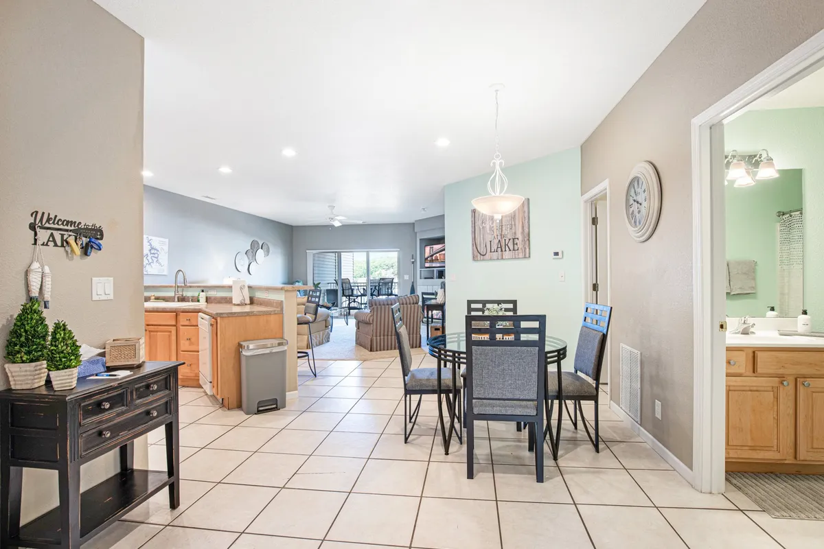 A cozy dining area with a dining table and chairs, kitchen area in view, lake-themed decor, and a decorative sign that adds a personal touch. The setting invites family meals, social gatherings, and game nights, encapsulating the spirit of shared experiences.