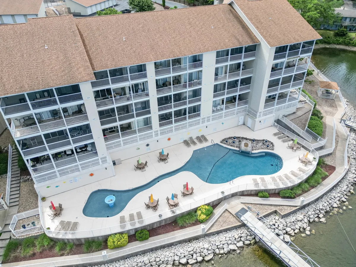 This image captures an inviting poolside scene with lounge chairs overlooking the water, set against the backdrop of the building's facade. The tranquil waterfront and resort-style amenities are prominent, evoking a sense of leisure and scenic relaxation.