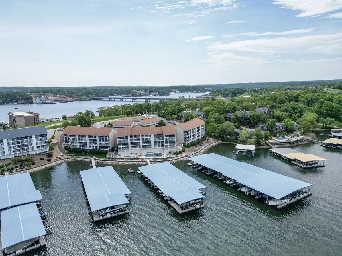 A sweeping exterior view of the waterfront with marinas, resort buildings, and lush green landscape. The image highlights boats on the water and the appealing environment for both active and relaxing moments by the lake.